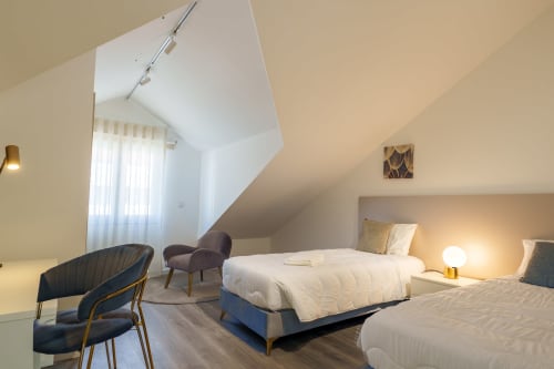 Modern attic bedroom at Suites Avenue Lux Apartments in Horta with twin beds, seating area, and skylight