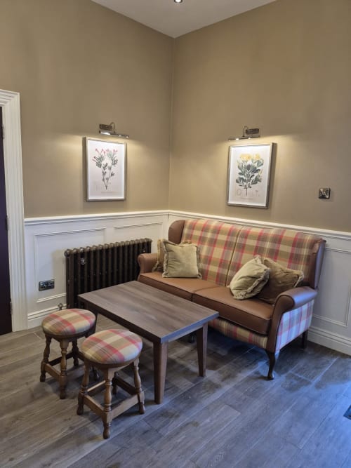 Cozy lounge area at Sliabh Beagh Hotel with plaid sofa, botanical prints, radiator, and tartan ottomans in Monaghan, Ireland.