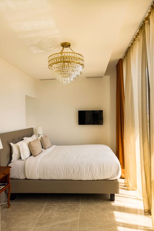 Chambre élégante à l'Hôtel Villa Martini à Ajaccio avec vue sur mer, lit capitonné gris, lustre en cristal