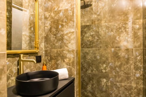 Salle de bains élégante à l'Hôtel Villa Martini à Ajaccio avec vasque noire, robinetterie dorée et murs en marbre
