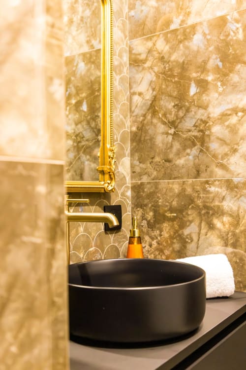 Lavabo de luxe aux vasque noire et robinetterie dorée à l'Hôtel Villa Martini Ajaccio, avec murs en marbre et miroir