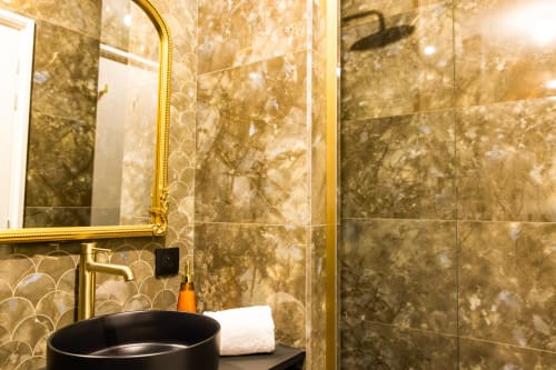 Salle de bain luxueuse à l'Hôtel Villa Martini d'Ajaccio, avec miroir doré, lavabo noir, carrelage en marbre et douche pluie