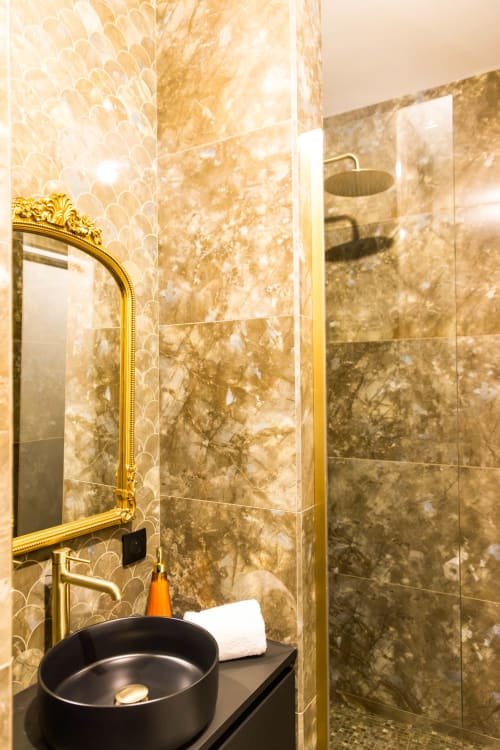 Salle de bains luxueuse de l'Hôtel Villa Martini à Ajaccio avec carrelage en marbre, miroir encadré doré et vasque noire