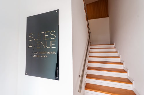 Suites Avenue Lux Apartments entrance with dark signage and wooden staircase in Horta
