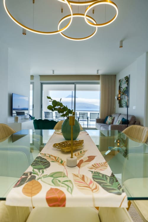 Modern dining room in Horta apartment with sea view, contemporary neon lighting, botanical table runner, and ocean vista