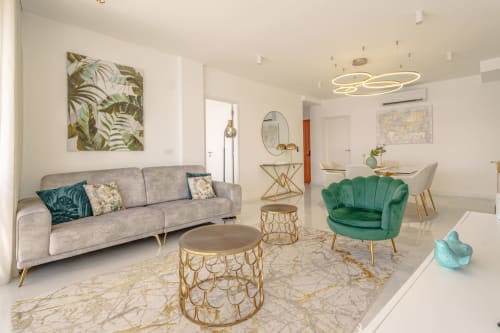 Modern living room in Suites Avenue Lux Apartments, Horta, with gray sofa, green accent chair, and gold side tables
