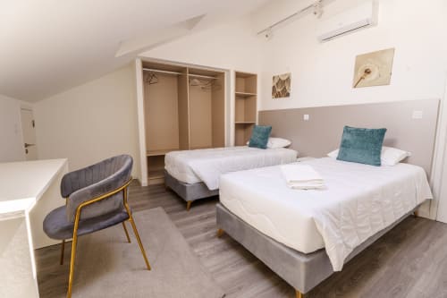 Modern bedroom at Suites Avenue Lux Apartments in Horta with two beds, teal pillows, and contemporary furnishings