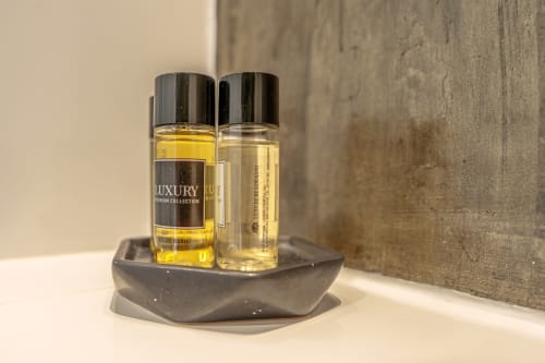 Luxury bath gel and shower gel bottles on dark tray in bathroom at Suites Avenue Lux Apartments, Horta