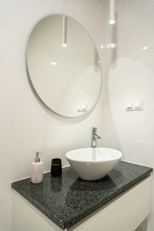 Modern bathroom sink with white vessel bowl and oval mirror at Suites Avenue Lux Apartments in Horta