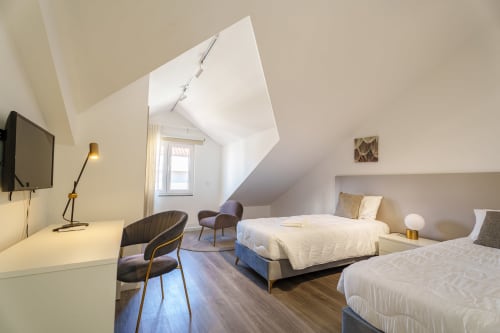 Modern attic bedroom at Suites Avenue Lux Apartments in Horta with twin beds, desk, and sea views