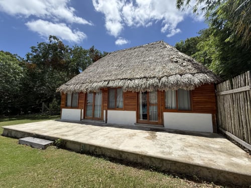 Bungaló Casa Manglar con techo de paja en el hostal Cayuco Maya de Bacalar, México, con terraza de madera y vistas al lago