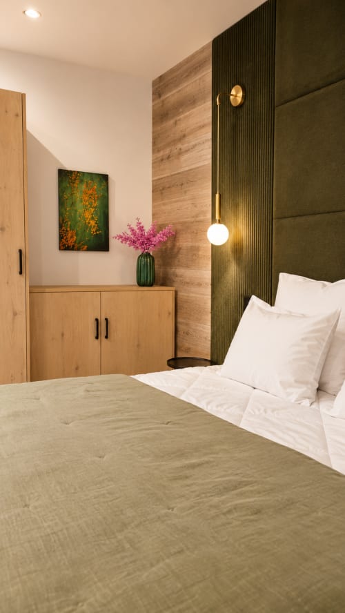 Chambre moderne à la Villa Alora à Calenzana avec tête de lit vert olive, mobilier en bois et fleurs roses