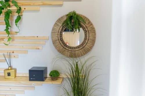 Decor boho moderno ad Aurum Nolana Suites Pompeii con specchio intrecciato, piante e scaffali in legno