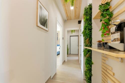 Corridoio moderno dell'Aurum Nolana Suites a Pompei con soffitto in legno, piante verdi alle pareti e design minimalista