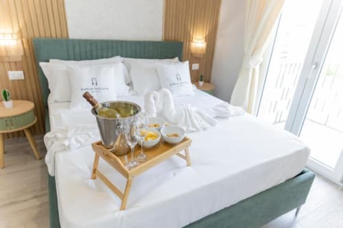 Esclusiva suite presso Aurum Nolana Suites a Pompei con servizio champagne sul vassoio letto, testata verde e biancheria bianca