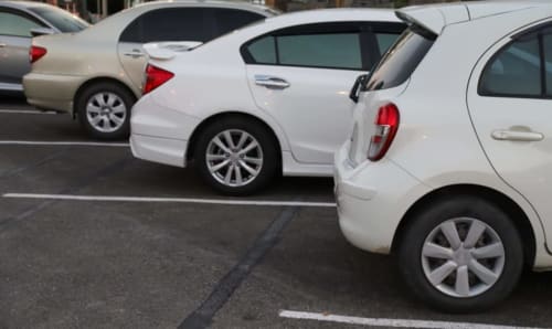 Auto bianche parcheggiate nel parcheggio dell'Aurum Nolana Suites, hotel di Pompei, con luci di coda rosse visibili