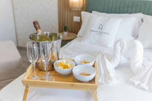 Camera da letto lussuosa alle Aurum Nolana Suites con champagne, flute e stuzzichini su vassoio di legno accanto al letto