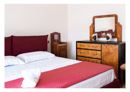 Elegante camera da letto dell'appartamento StaysinSicily Lipari a Milazzo con testiera bordeaux, biancheria bianca, coperta rossa, arredamento in legno