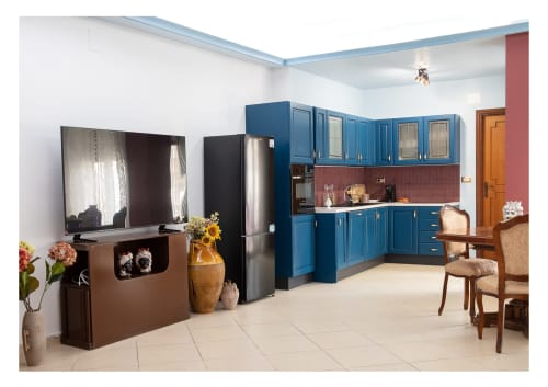 Moderno appartamento a Milazzo con cucina dalle ante blu, elettrodomestici in acciaio inox e zona living con TV e tavolo da pranzo