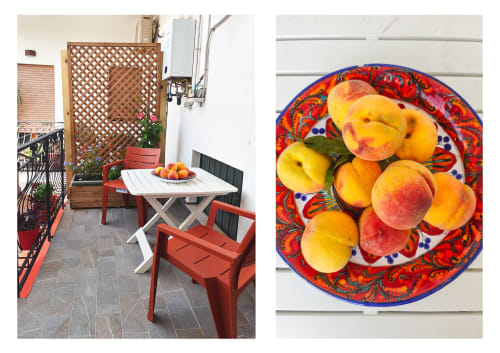 Area esterna per pranzi siciliani con sedie rosse, tavolo bianco e pesche fresche nel piatto colorato