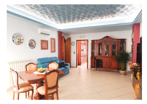 Ampia zona living nell'appartamento di Lipari, Milazzo Sicilia con tavolo da pranzo, divano blu, mobili in legno e soffitto moderno