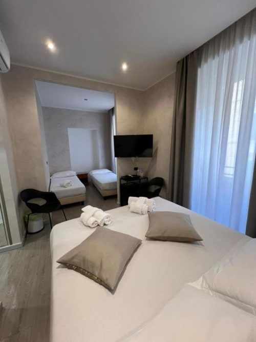 Camera quadrupla dell'Hotel Ercoli House, Roma - spaziosa con letto matrimoniale, letti singoli, TV e finestre a tutta altezza