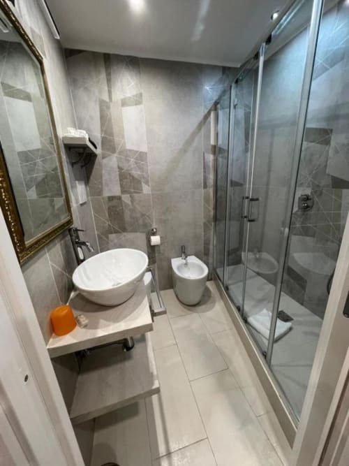 Bagno moderno con doccia walk-in, lavabo sospeso e bidet nella camera quadrupla di Hotel Ercoli House, Roma