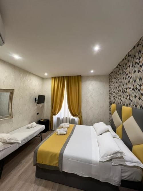 Camera tripla moderna dell'Hotel Ercoli House a Roma con accenti gialli, letto matrimoniale e arredamento contemporaneo