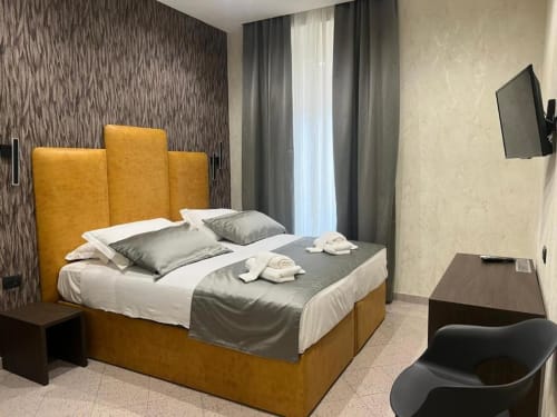 Camera tripla dell'Hotel Ercoli House a Roma con letto dalla testiera dorata, pareti ristruttrate, comfort moderni e TV a schermo piatto