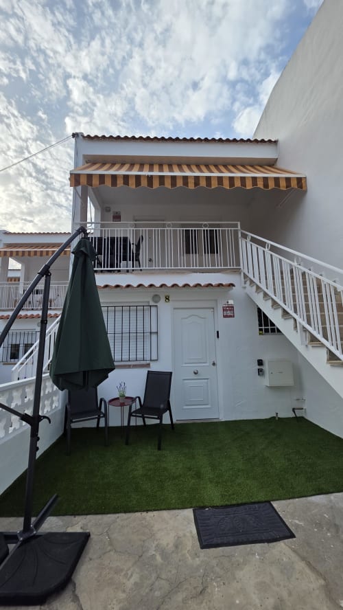 Bungalow blanco unidad 8 con toldo a rayas, terraza y vistas al jardín en Benicàssim, España