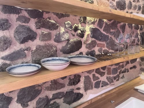 Ripiano in legno con ciotole di ceramica su muro in pietra rustica all'hotel Habemus di Rocca di Papa, Italia