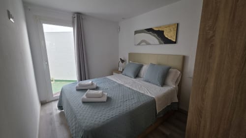 Dormitorio moderno en casa de campo de Benicàssim con cama queen, terraza con vista al jardín, ropa de cama azul y decoración contemporánea