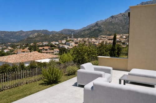 Terrasse de la Villa Alora avec salon blanc donnant sur le village de Calenzana et les montagnes, Corse