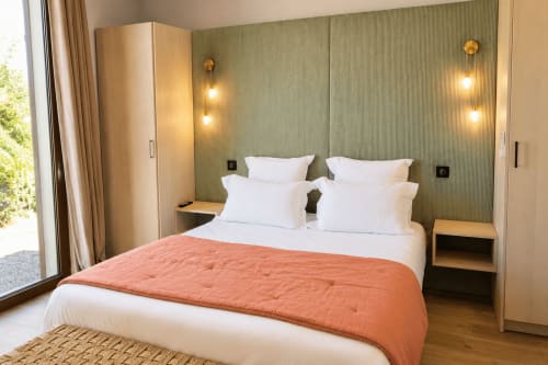 Chambre moderne à la Villa Alora B&B à Calenzana avec lit queen-size, oreillers blancs, parure orange et mur d'accent vert