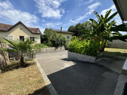 Vue du jardin de la Villa des Palmiers à Villeneuve-sur-Lot avec palmiers et bâtiments en pierre sous ciel bleu