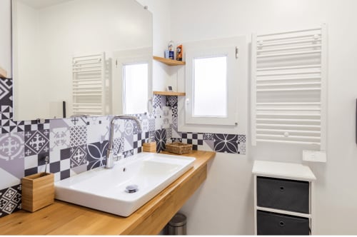 Salle de bains moderne au gîte Villa des Palmiers avec carrelage à motifs, meuble vasque en bois et radiateurs blancs