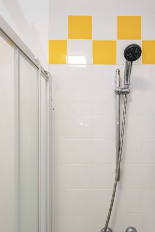 Salle de bain moderne avec carrelage jaune et pommeau de douche à main à la Villa des Palmiers, Villeneuve-sur-Lot