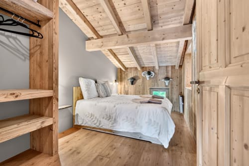 Chambre chaleureuse en bois à L'Alp'In B&B à La Plagne avec poutres apparentes, literie blanche et mobilier rustique en sapin.