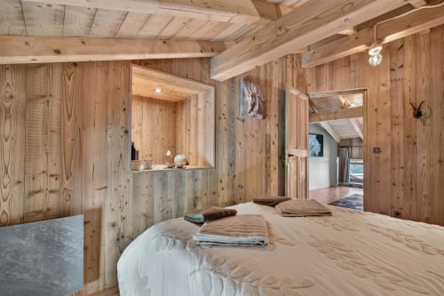 Chambre alpine chaleureuse à L'Alp'In à La Plagne avec murs en bois, lit queen-size et salle de bains attenante