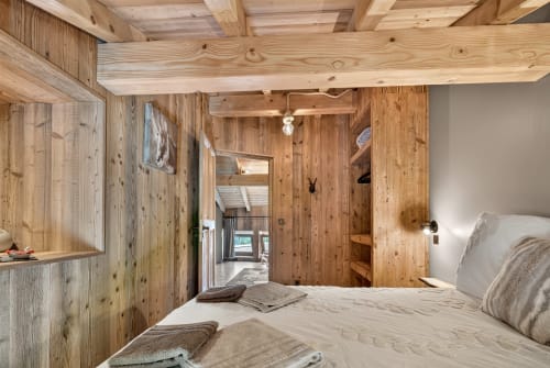 Chambre cosy en bois à L'Alp'In B&B à La Plagne avec murs en pin rustique, lit confortable et vue sur le jardin
