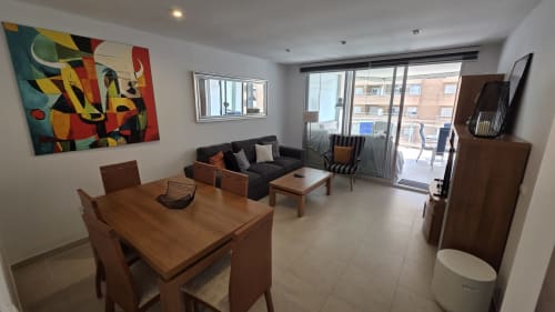 Moderno apartamento frente al mar en Benicàssim con comedor, sofá negro, obras de arte y balcón con vista al mar
