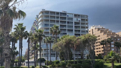 Edificio moderno de apartamentos en primera línea de playa en Benicàssim con palmeras y arquitectura mediterránea