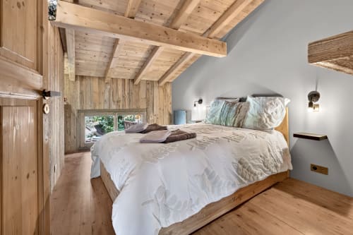 Chambre en bois avec poutres apparentes et vue sur le jardin à L'Alp'In, La Plagne Tarentaise. Lit queen-size avec literie blanche et