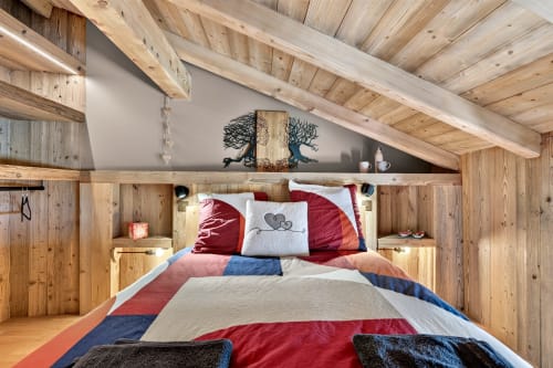 Chambre alpine rustique aux poutres en bois, linge de lit bicolore rouge et marine, et panneaux en bois massif à L'Alp'In, La