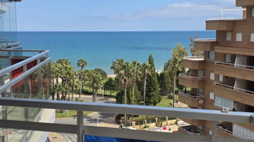 Vista al mar desde el balcón de un apartamento frente a la playa en Benicàssim con palmeras y costa mediterránea