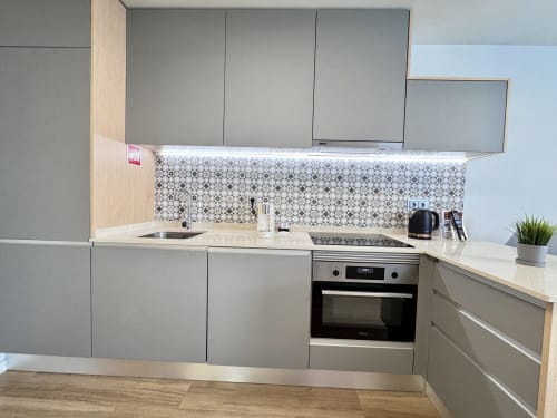Cuisine moderne de l'appartement Premium Silver à RIA CENTRUM Smart Residence, Aveiro, avec armoires grises et carrelage de crédence à motifs
