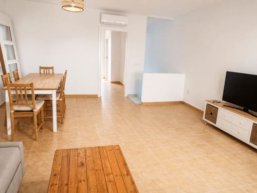 Spacious living room at Apartamento Alzara in Sanlúcar de Barrameda with dining table, TV, and tile flooring