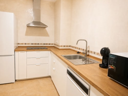 Modern kitchen in Alzara cottage at Living Sur, Sanlúcar de Barrameda, with white cabinetry, wooden countertops, and