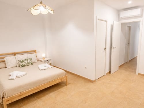 Modern bedroom in Alzara cottage at Living Sur, Sanlúcar de Barrameda, with wooden bed, white walls, and tile flooring