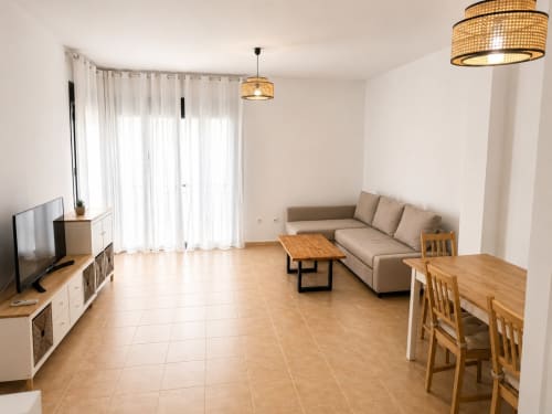 Bright living room in Alzara cottage at Living Sur, Sanlúcar de Barrameda, with sofa, dining table, TV, and modern amenities